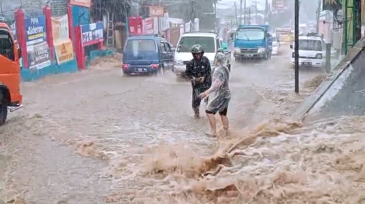 Ruas Jalan Raya Cipanas-Cianjur di sekitar areal Desa Ciherang, Kecamatan Pacet dilanda banjir akibat meluapnya air dari drainase, Kamis (15/5/2025)