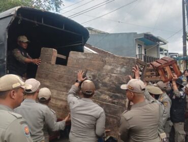 Petugas Satpol PP Cianjur mengangkut lapak dagangan pedagang Bomero Cistywalk, Cianjur, Jawa Barat. Penertiban pedagang yang dilaksanakan Selasa (11/11/2025) berlangsung ricuh dan diwarnai bentrok fisik kedua belah pihak.(Foto: Kompas)