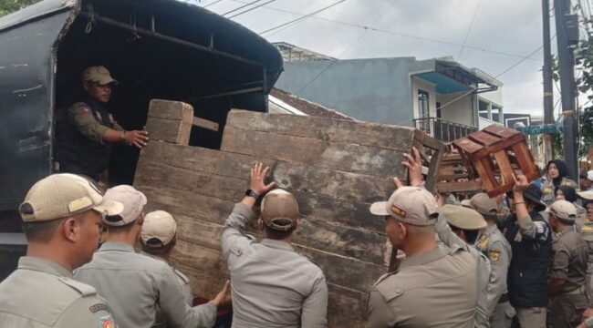 Petugas Satpol PP Cianjur mengangkut lapak dagangan pedagang Bomero Cistywalk, Cianjur, Jawa Barat. Penertiban pedagang yang dilaksanakan Selasa (11/11/2025) berlangsung ricuh dan diwarnai bentrok fisik kedua belah pihak.(Foto: Kompas)