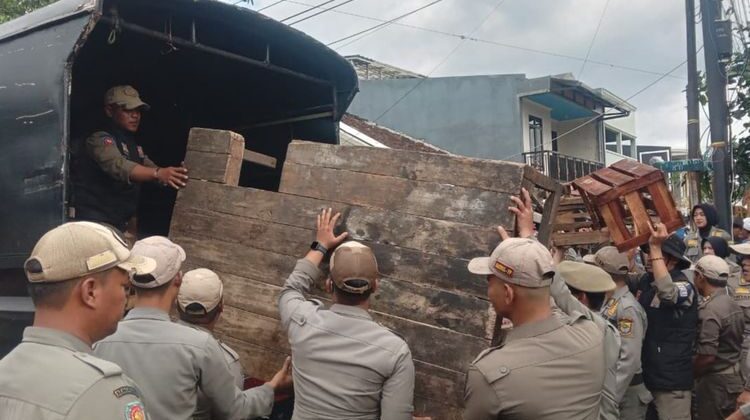 Petugas Satpol PP Cianjur mengangkut lapak dagangan pedagang Bomero Cistywalk, Cianjur, Jawa Barat. Penertiban pedagang yang dilaksanakan Selasa (11/11/2025) berlangsung ricuh dan diwarnai bentrok fisik kedua belah pihak.(Foto: Kompas)